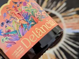 Close-up of the Delância orange wine botanical illustrated label showing cardamom and bergamot details